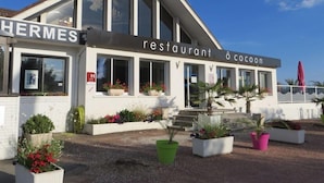 A restaurant with a modern architectural design, featuring large windows and a sign that reads 'restaurant à cocon.' - Brit Hotel Hermes (Couchey)