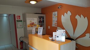 Una reception hotel con un cartello per la colazione, un estintore e una telecamera di sicurezza.