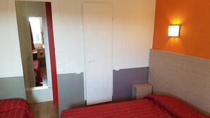 Una camera d'albergo con due letti, un armadio, un comodino e uno specchio.