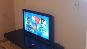 Ein Fernseher auf einem schwarzen Ständer, in der Nähe eine Steckdose.
