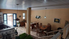 A spacious living area with a dining table and chairs, a kitchen with a sink and stove, and a staircase leading to an upper level. - Country house in a gated community with a private lake, accommodates up to 20 people. (Ibiúna)