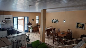 A spacious living area with a dining table, chairs, a kitchen with a stove, and a view of the outside. - Country house in a gated community with a private lake, accommodates up to 20 people. (Ibiúna)