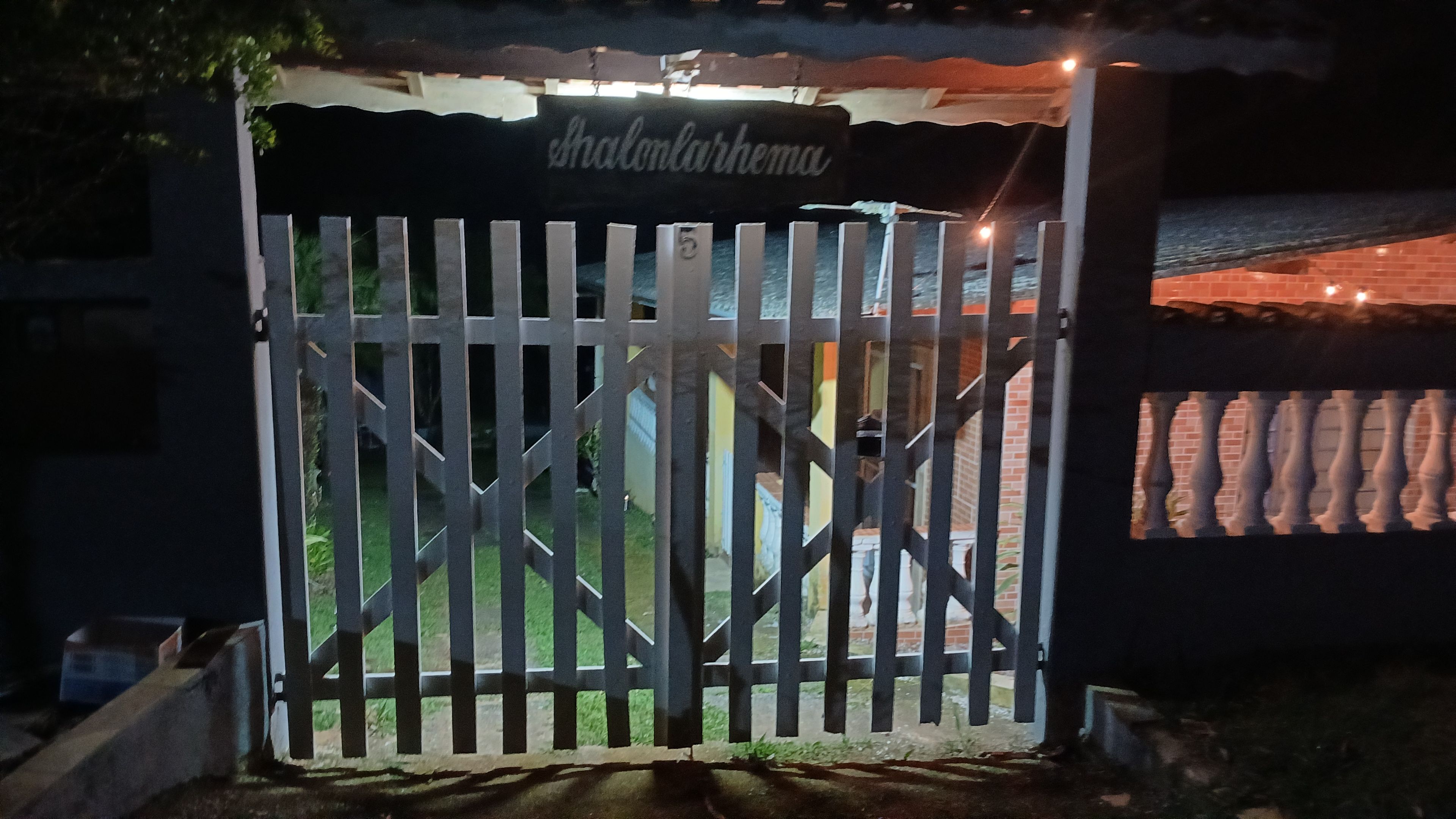 A gated entrance with a metal gate and a sign above it.