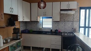 A kitchen with white cabinets, a black countertop, a gas stove, and a window with a view. - Country house in a gated community with a private lake, accommodates up to 20 people. (Ibiúna)