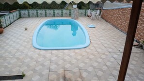 A swimming pool with a tiled deck, surrounded by a brick wall and a decorative fence. - Country house in a gated community with a private lake, accommodates up to 20 people. (Ibiúna)