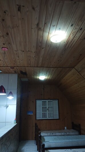 A wooden room with a bed, a window with blinds, and a sign indicating a smoking area. - Country house in a gated community with a private lake, accommodates up to 20 people. (Ibiúna)