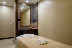 A hotel room with a large mirror, a bed with a towel, and a wall with a patterned tile design. - Renaissance Hoi An Resort & Spa (Hoi An)