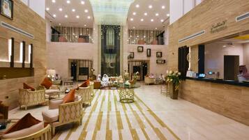 A spacious lobby with a reception desk, seating area, and a large chandelier.