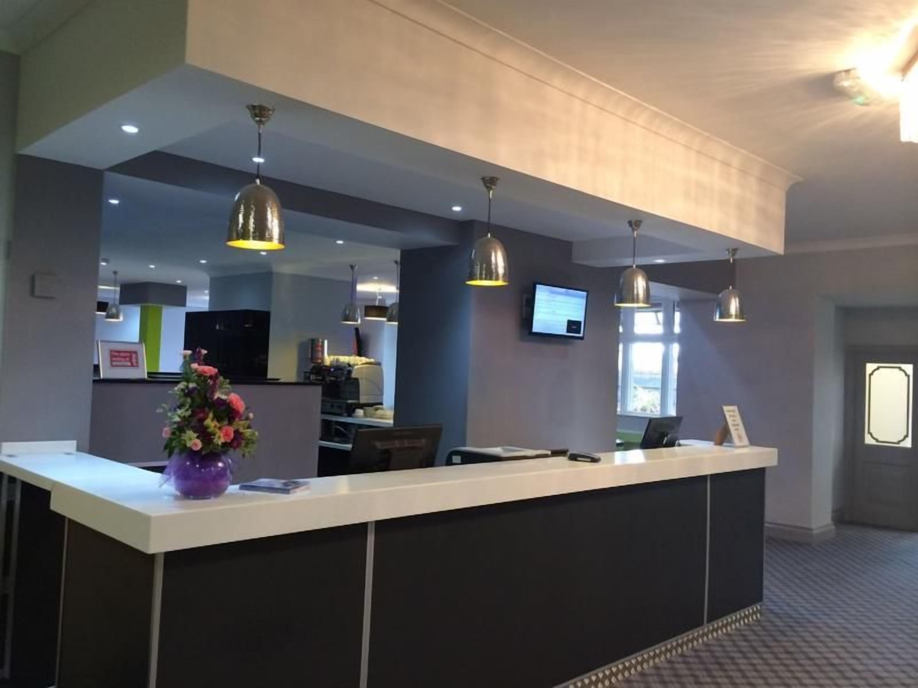 A reception desk with a flat-screen TV, a flower arrangement, and pendant lighting.