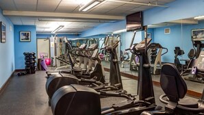 Ein Fitnessstudio mit verschiedenen Trainingsgeräten, darunter Laufbänder, Ergometer und Kraftgeräte.