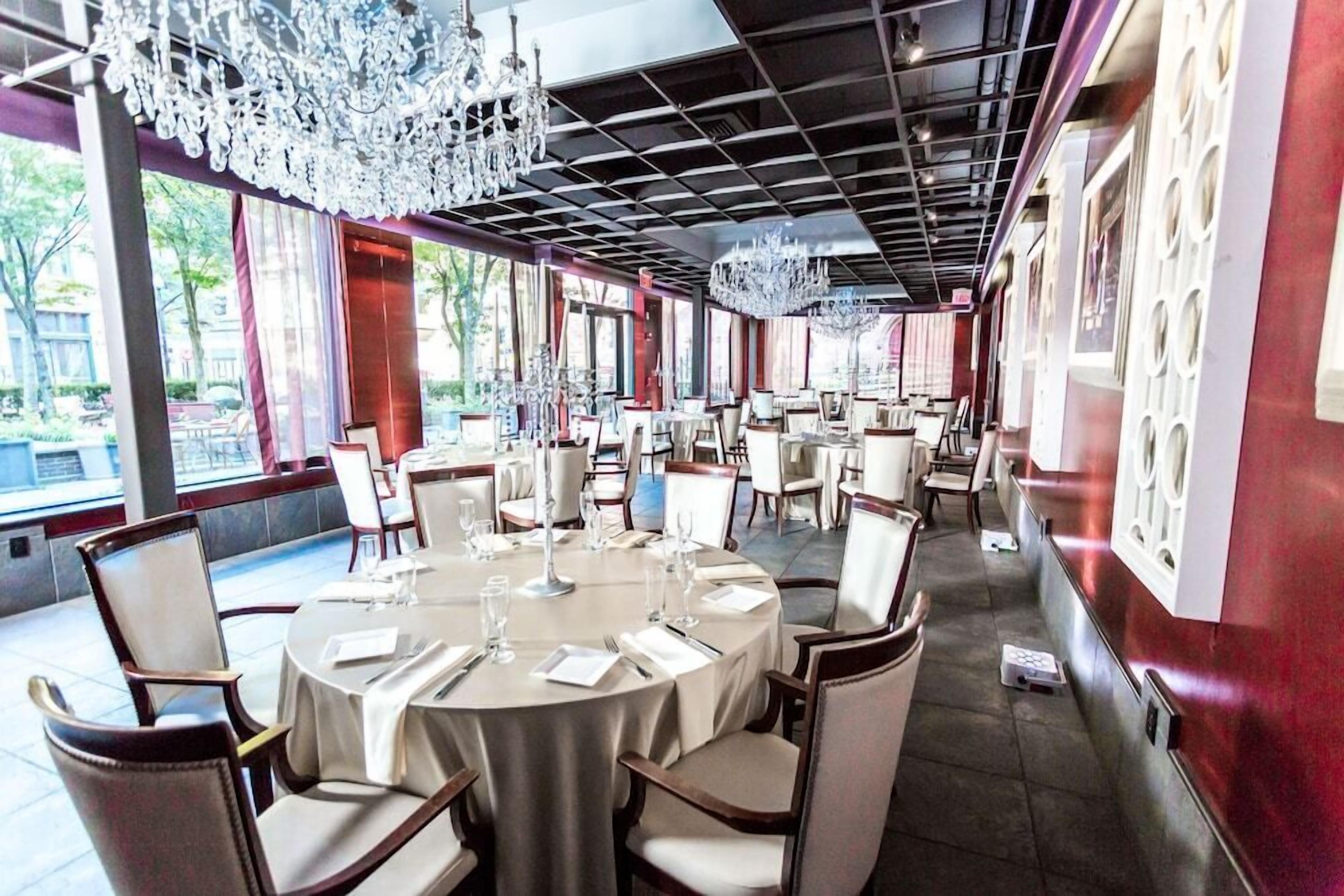 A restaurant with round tables, chairs, and chandeliers.