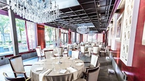 Un restaurant avec des tables rondes, des chaises et des lustres.