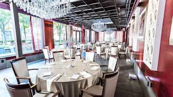 A restaurant with round tables, chairs, and chandeliers.