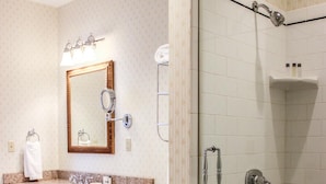 Une salle de bain avec un lavabo sur un plan de travail en granit, un miroir, des toilettes et une douche à parois de verre.