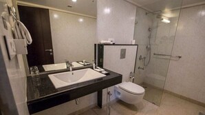A modern bathroom with a black countertop, a white sink, a toilet, and a glass-enclosed shower area. - Sagar Sona (Lucknow)
