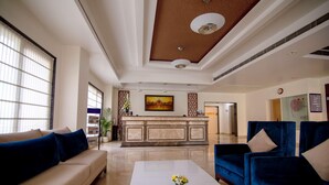 A hotel lobby with a reception desk, seating area, and a clock on the wall. - Sagar Sona (Lucknow)