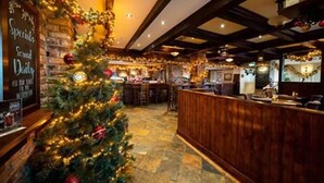 A Christmas tree with lights and ornaments in a hotel lobby with a wooden reception desk and stone flooring. - The White Sands Hotel Portmarnock (Portmarnock)