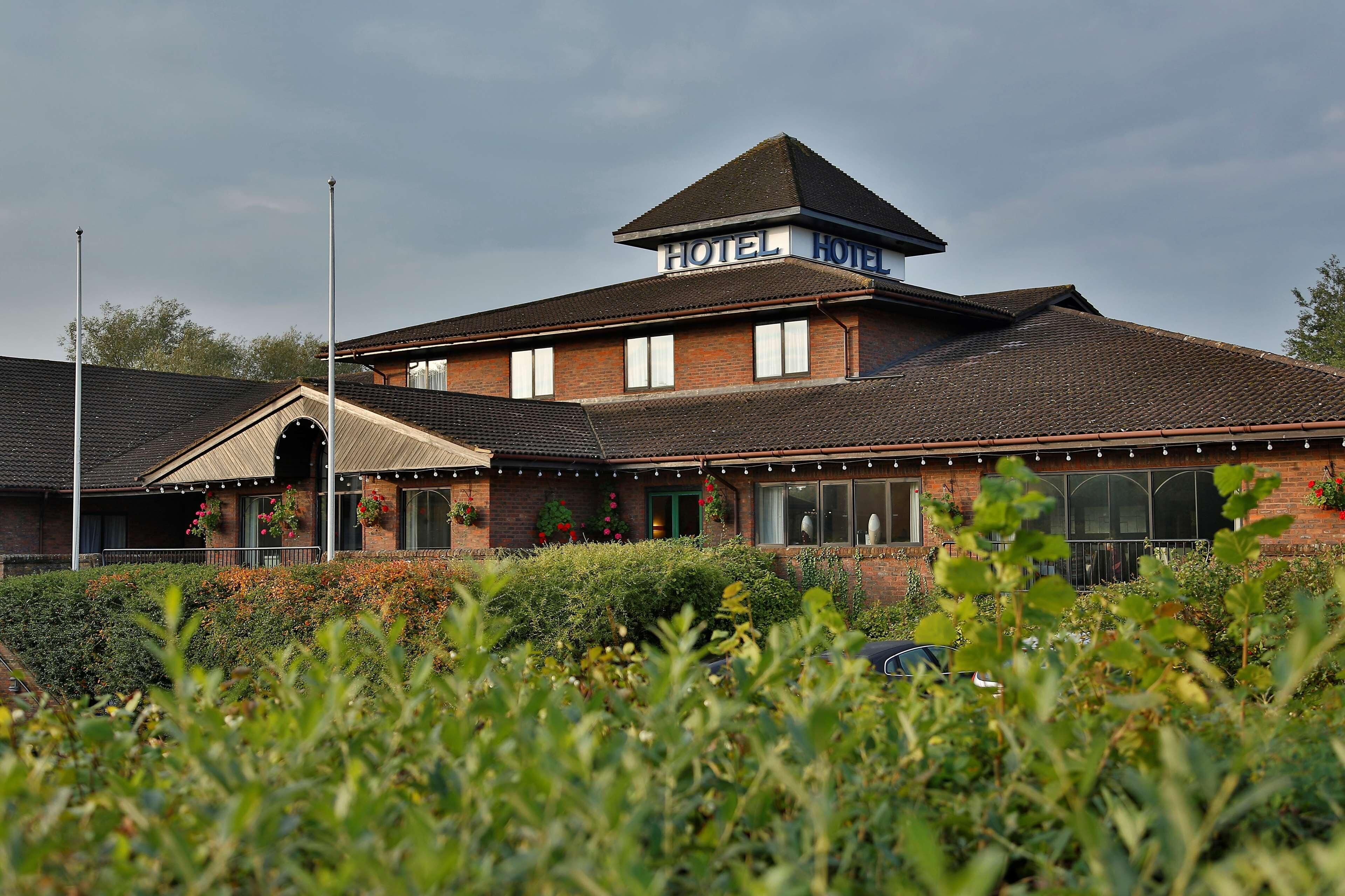 A hotel with a prominent sign, a brick facade, and a traditional roofline.