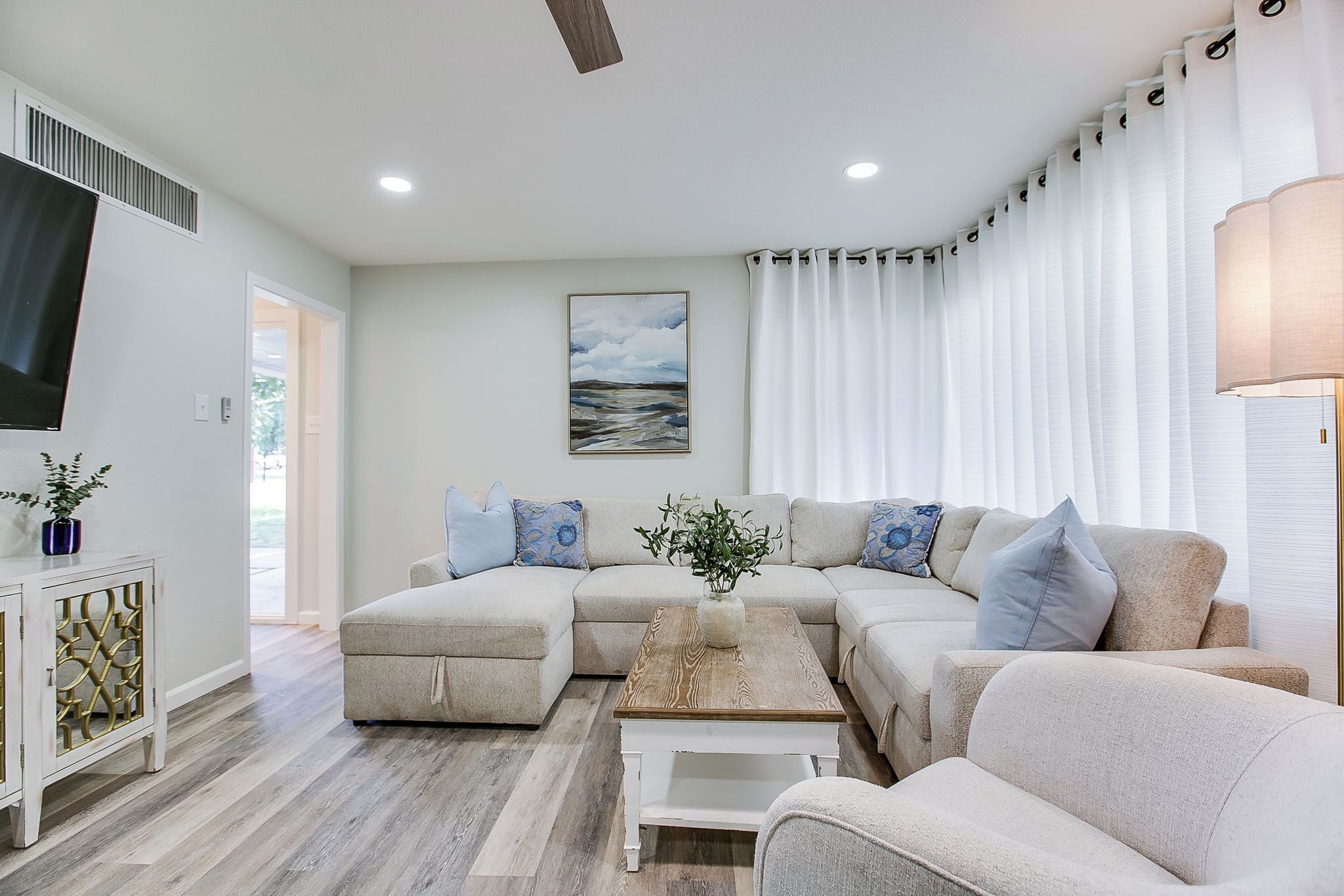 A living room with a sectional sofa, a coffee table, and a TV mounted on the wall.
