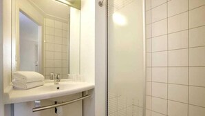 Een badkamer met een wit wastafel, spiegel en douchegedeelte.