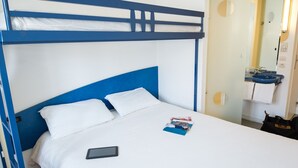 Een stapelbed met wit beddengoed en een tablet op het onderste bed.