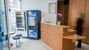 Een receptiebalie met een automaat en een potplant.
