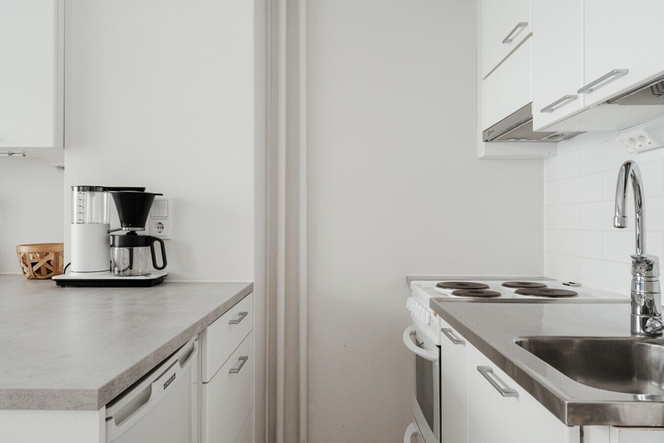 A compact kitchen with a coffee maker, a stove, and a sink.