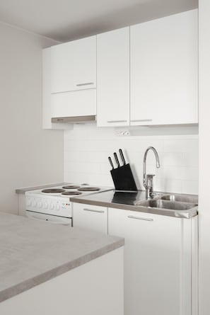 Una cocina moderna con armarios blancos, un lavamanos de acero inoxidable y una estufa.