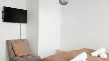 A modern bedroom with a bed, a chair, a TV, and a hanging light fixture.
