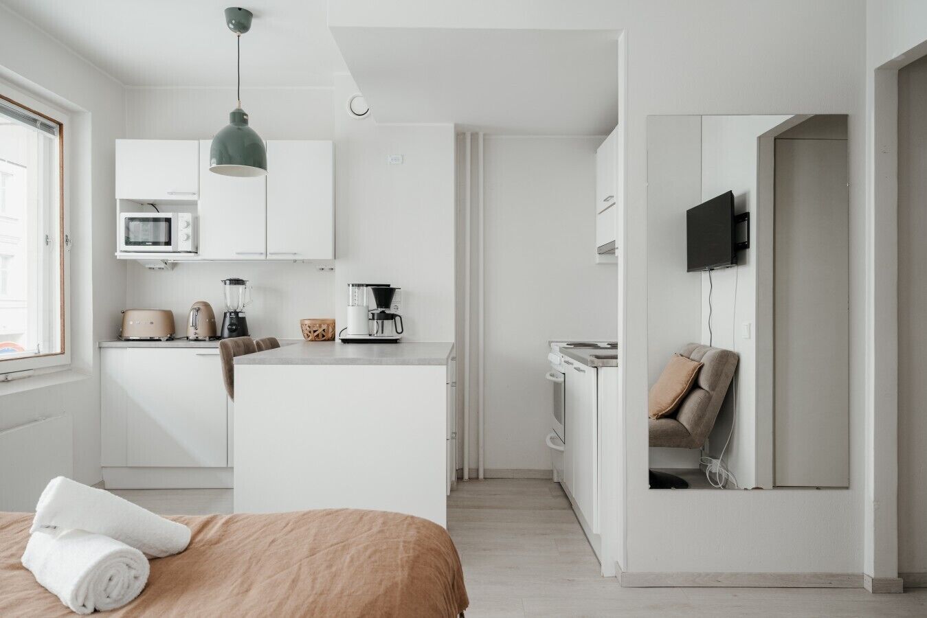 Une chambre à coucher moderne et minimaliste, avec un lit, une table de chevet et un téléviseur fixé au mur.