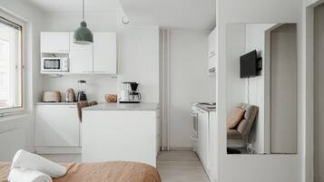 A modern, minimalist bedroom with a bed, a bedside table, and a TV mounted on the wall.