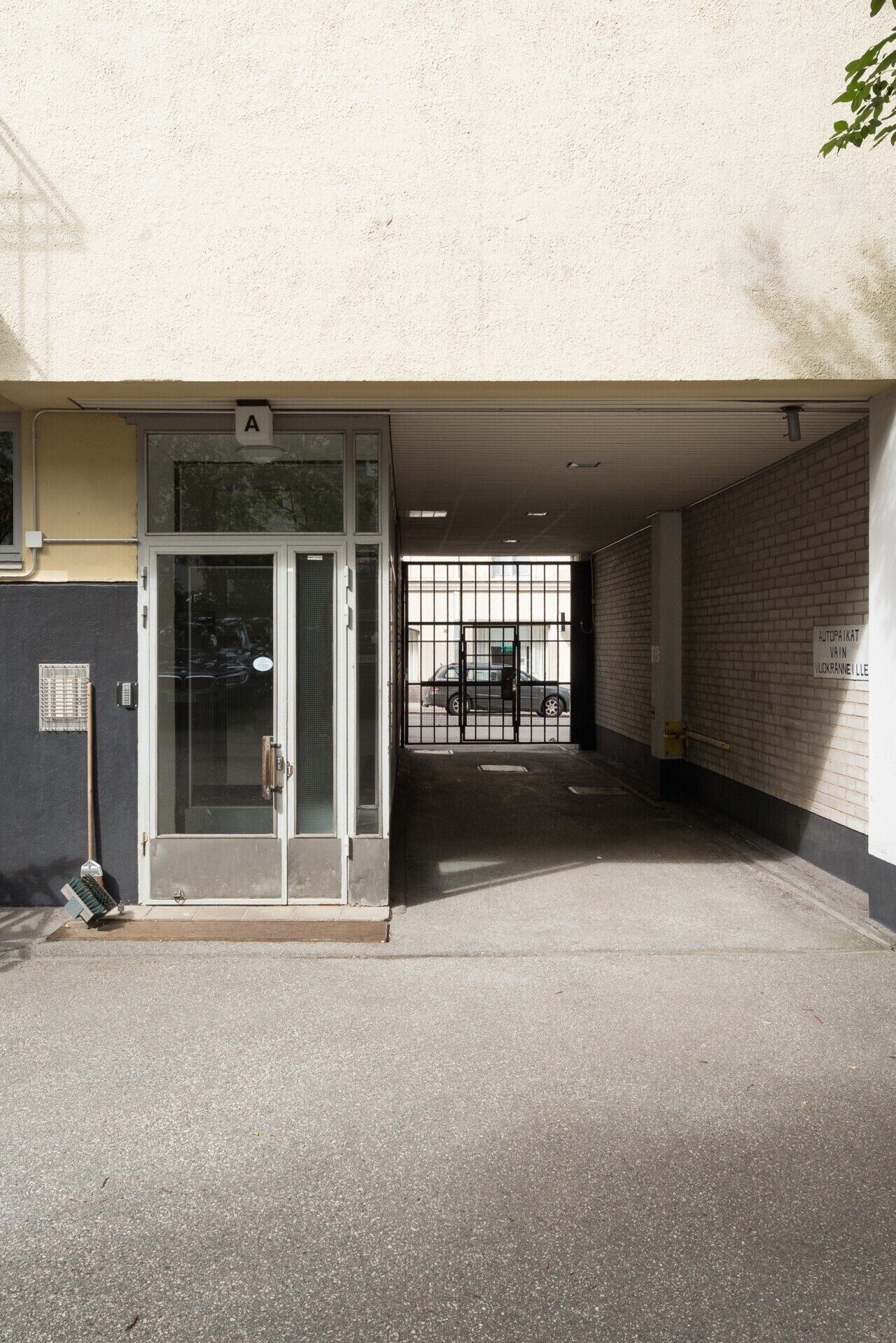 A parking garage entrance with a glass door, a metal gate, and a brick wall.