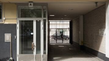 A parking garage entrance with a glass door, a metal gate, and a brick wall.