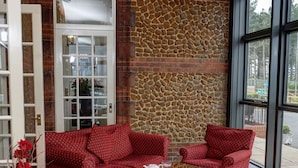 Una habitación acogedora con muebles de diseño rojo, una pared de piedra y un ventanal grande.