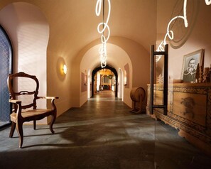 A corridor with a wooden chair, a mirror, and a decorative cabinet. - Hotel Fluela Davos (Davos)