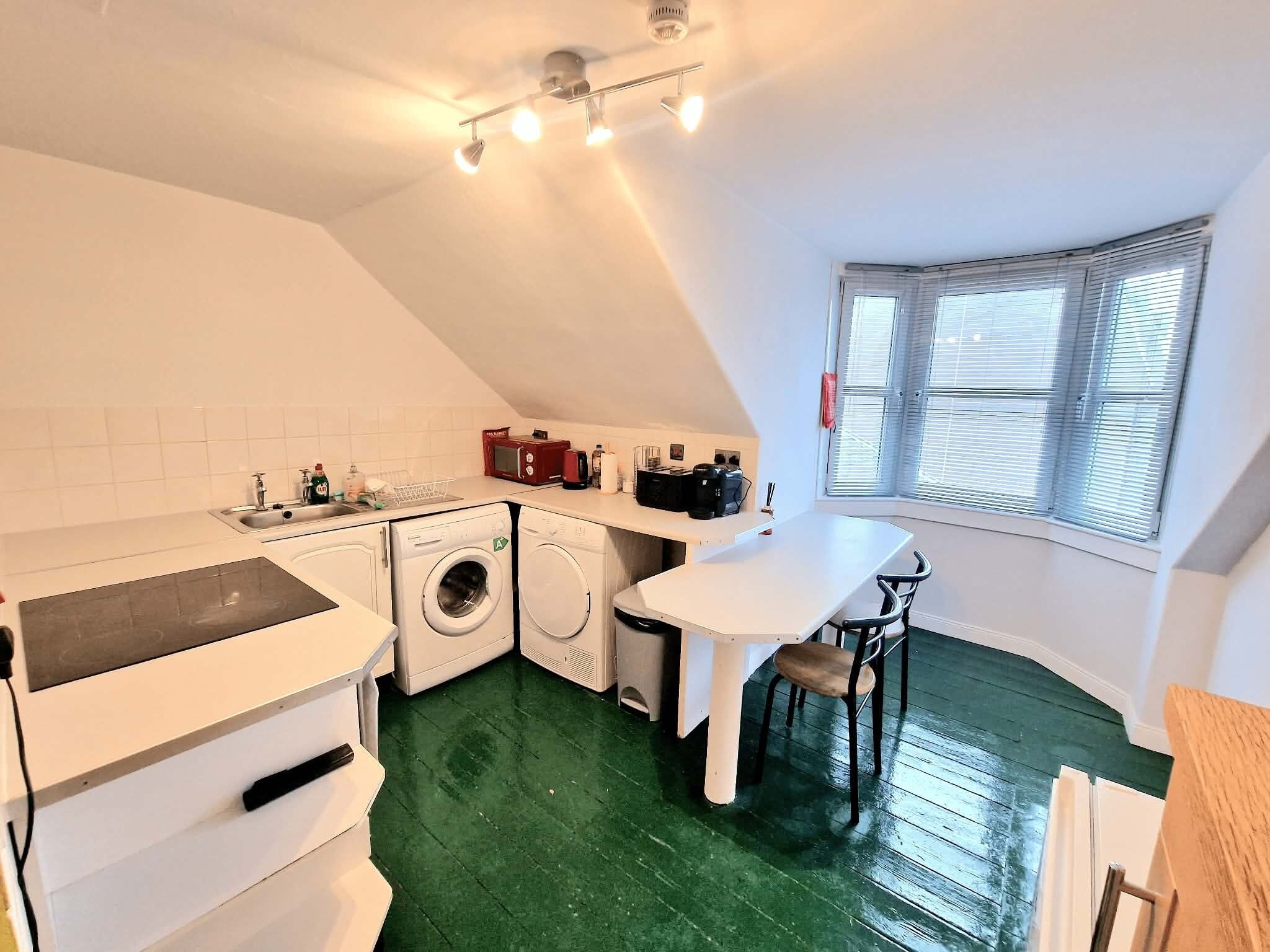 Een functionele keuken met een wasmachine, een koffiezetapparaat en een eethoek met uitzicht.
