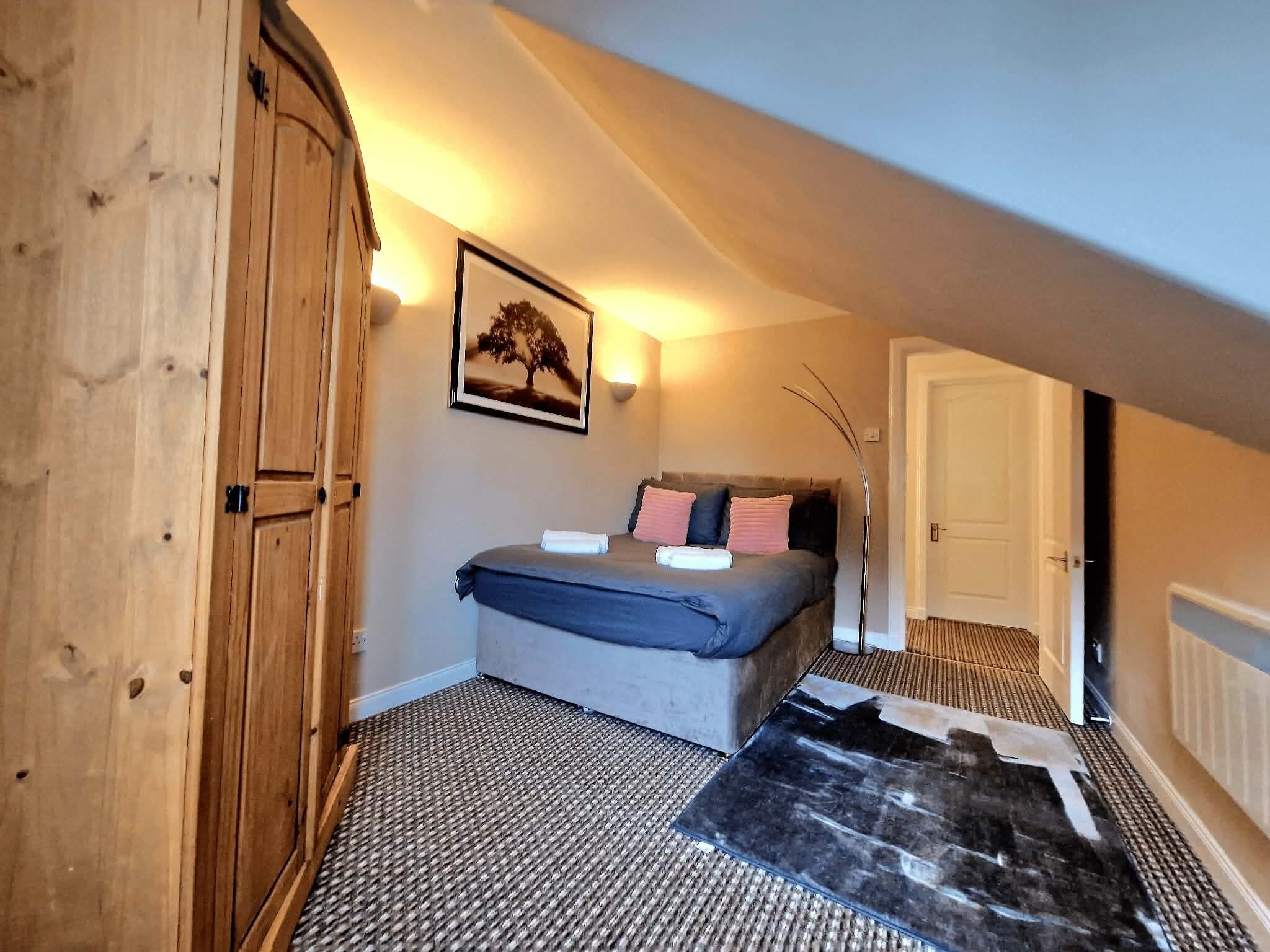Quarto com cama, guarda-roupa, um quadro na parede e radiador.