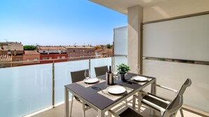 A balcony with a table set for two, overlooking a cityscape. - GRAN RESERVA MIMOSES ATIC B (Empuriabrava)