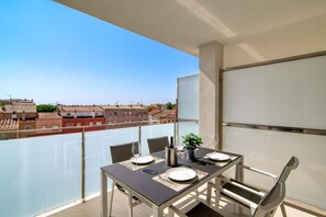 A balcony with a table set for two, overlooking a cityscape. - GRAN RESERVA MIMOSES ATIC B (Empuriabrava)