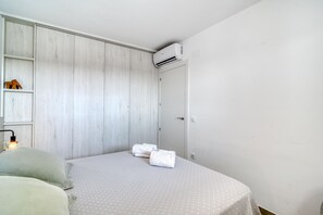 Une chambre à coucher comprenant un lit, une armoire et un appareil de climatisation.