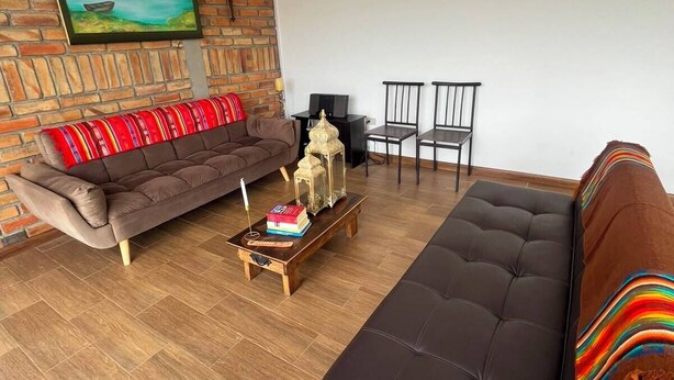 A modern living room with a brick wall, a large painting, a sofa, a coffee table, and a television.