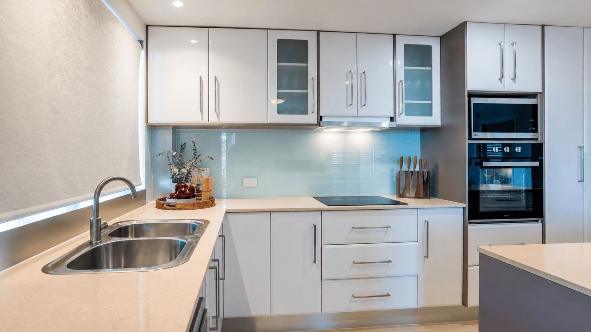 A modern kitchen with stainless steel appliances, white cabinetry, and a central island.