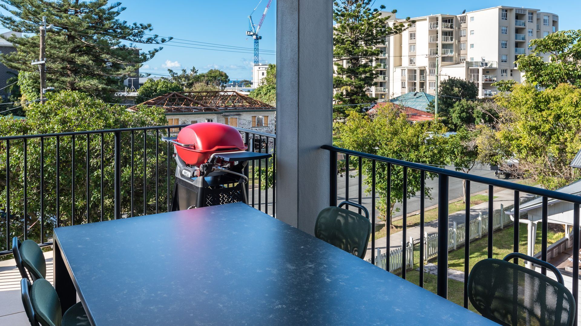 A balcony with a grill, a table, and chairs.