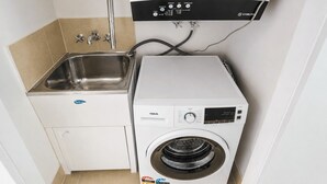 Ein kleiner Waschraum mit Waschmaschine, Spüle und Bedienfeld.