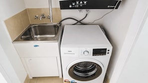 Ein kleiner Waschraum mit Waschmaschine, Spüle und Bedienfeld.