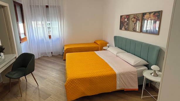 Habitación de hotel con dos camas, un escritorio, una silla y una ventana con cortinas.