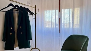 Una habitación con una percha, una silla y una ventana con cortinas de gasa.