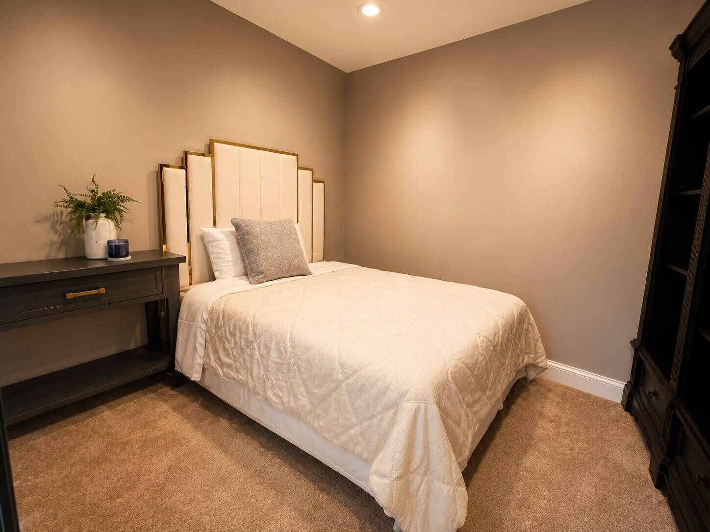 Une chambre à coucher avec un lit, une table de chevet et une commode.