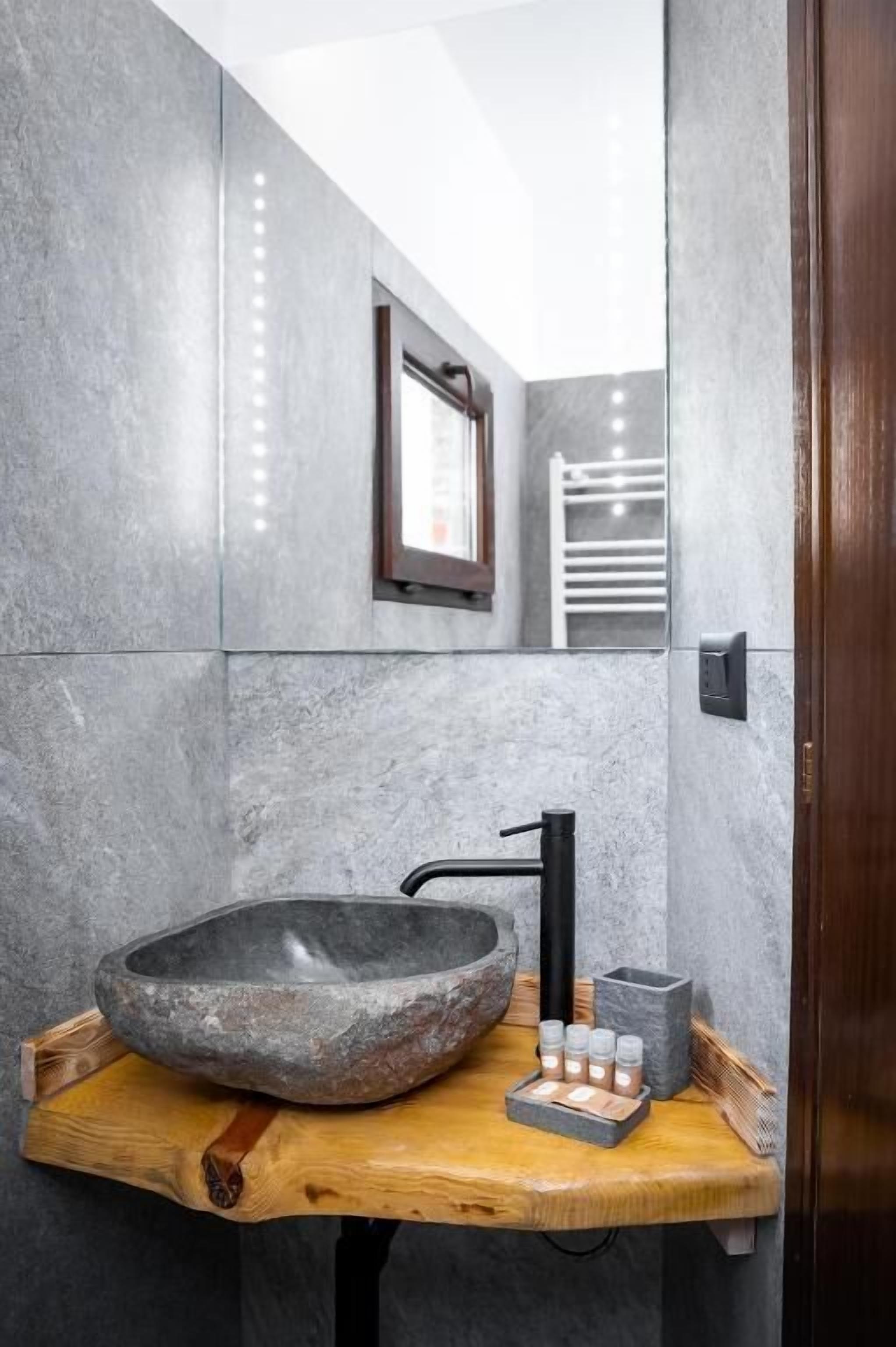 A bathroom with a stone basin, wooden countertop, and a mirror.