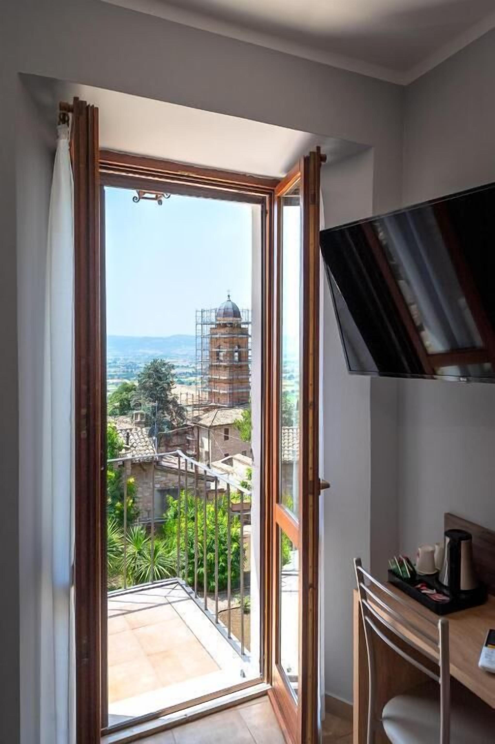 Una stanza con balcone, una scrivania e vista su un edificio in fase di ristrutturazione.